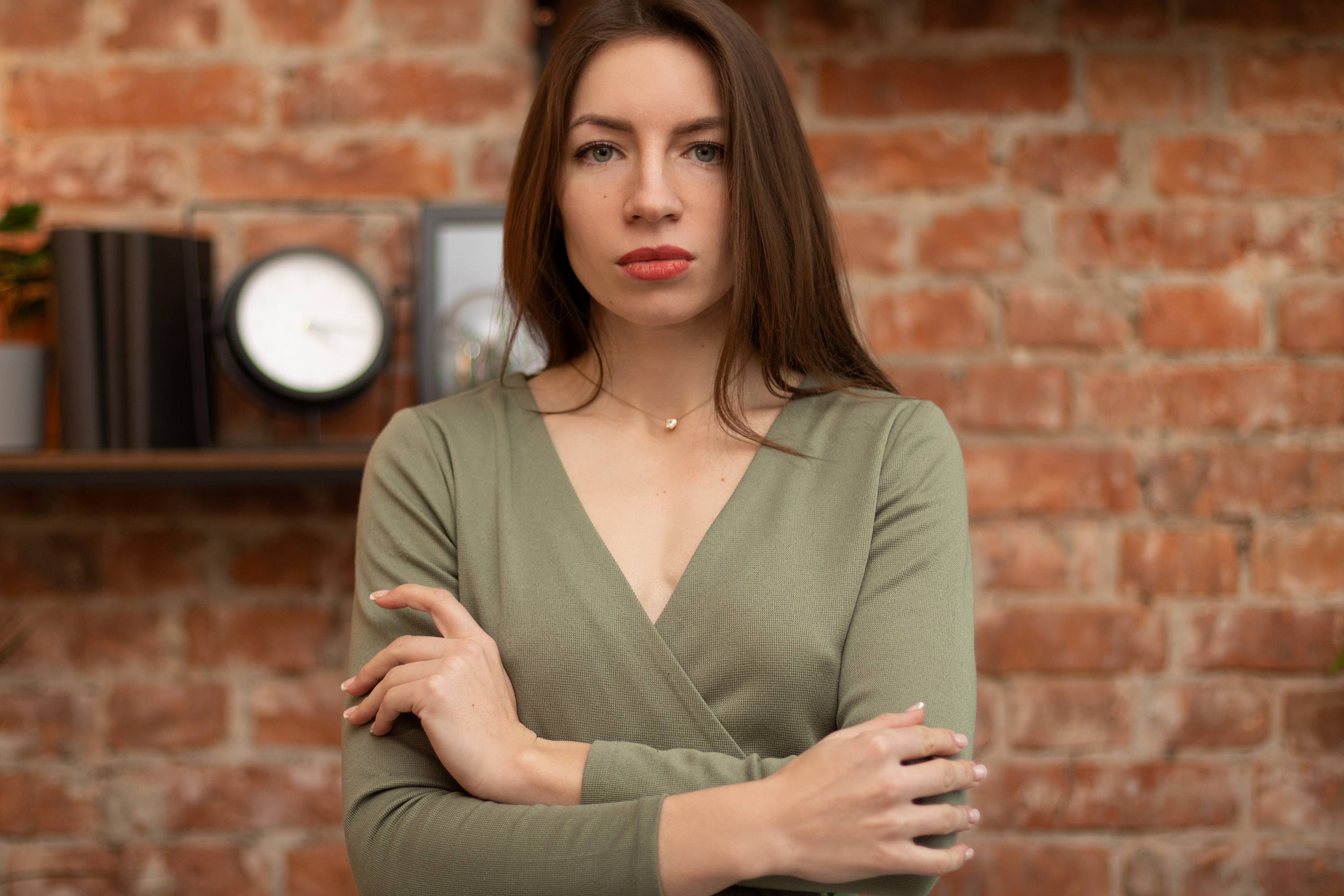 Young woman standing her ground with arms crossed in front of a brick wall, showing determination and strength. Young woman standing her ground with arms crossed in front of a brick wall, showing determination and strength.