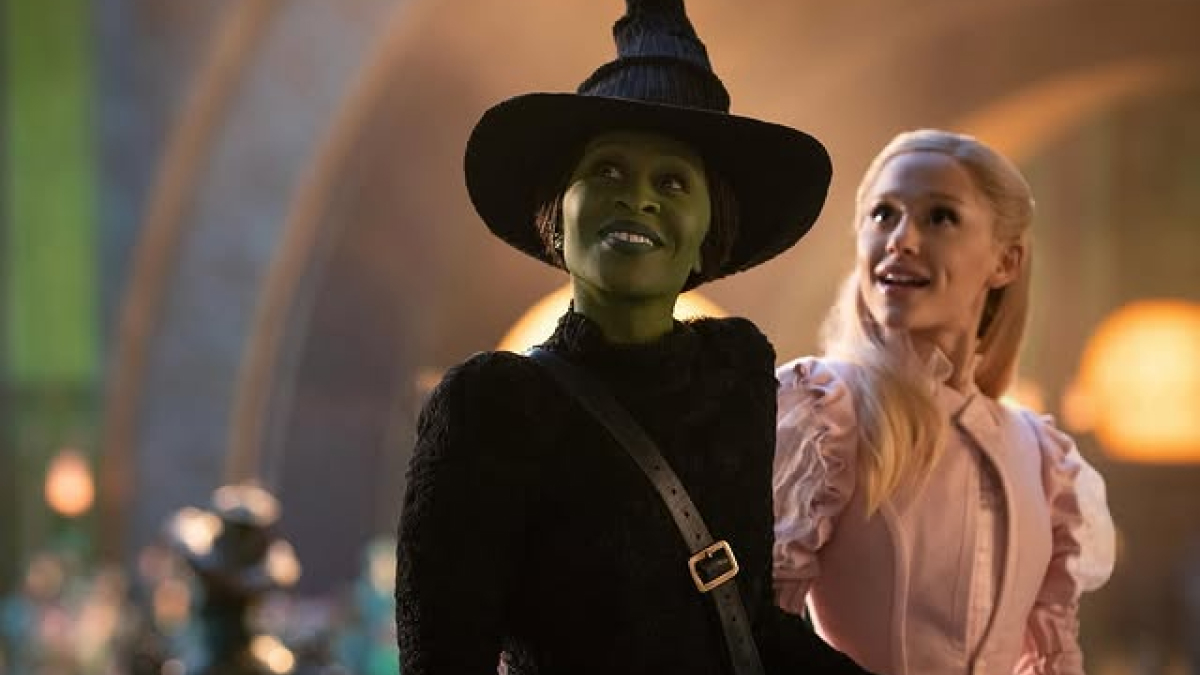 Two women, one with green skin in a witch costume and the other in a pink dress, highlighting themes of pretty privilege.