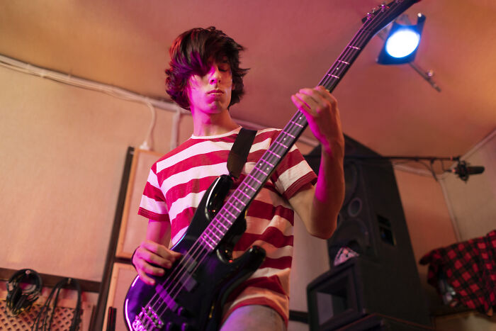 Teen playing electric guitar indoors, capturing energy and emotion related to rich kid meltdowns at private schools.