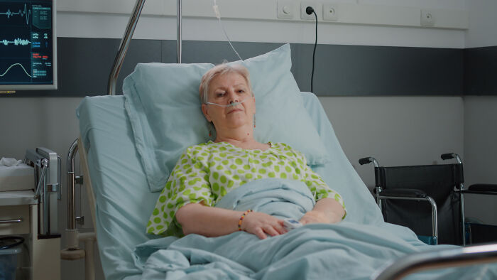 Elderly woman with nasal oxygen lying in hospital bed, representing unexpected rich kid meltdowns at private schools.