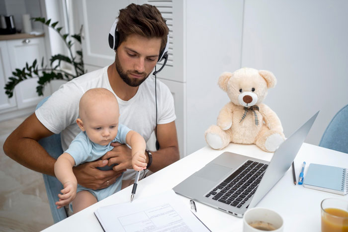 Man babysitting a baby while working on a laptop in a home office showing challenges of real work and babysitting. Man babysitting a baby while working on a laptop in a home office showing challenges of real work and babysitting.