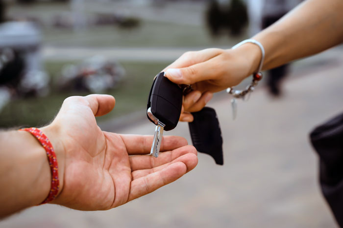 A person handing over car keys to another, symbolizing a jobless guy expecting a provider girlfriend to share her win. A person handing over car keys to another, symbolizing a jobless guy expecting a provider girlfriend to share her win.