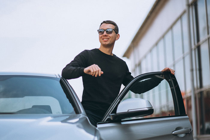 A jobless guy wearing sunglasses, standing by a car door, expecting provider girlfriend to share her $20K win. A jobless guy wearing sunglasses, standing by a car door, expecting provider girlfriend to share her $20K win.