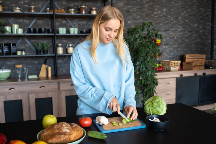 Young woman refusing to eat vegan meal preparing vegetables in kitchen on girlfriend birthday celebration.