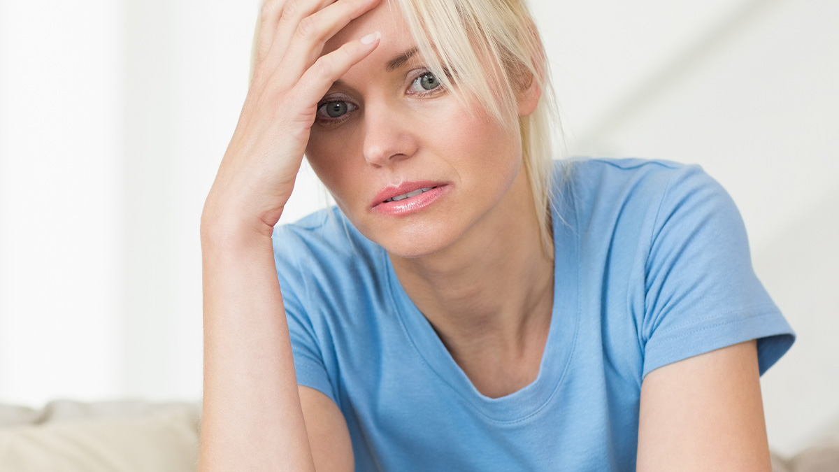 Woman in blue shirt looking stressed while setting boundaries with friend using her and toddler care demands