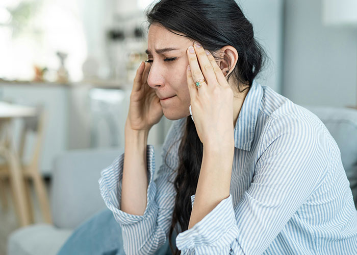 Woman feeling stressed and upset, holding her head while processing discovery about boyfriend's past stalking behavior. Woman feeling stressed and upset, holding her head while processing discovery about boyfriend's past stalking behavior.