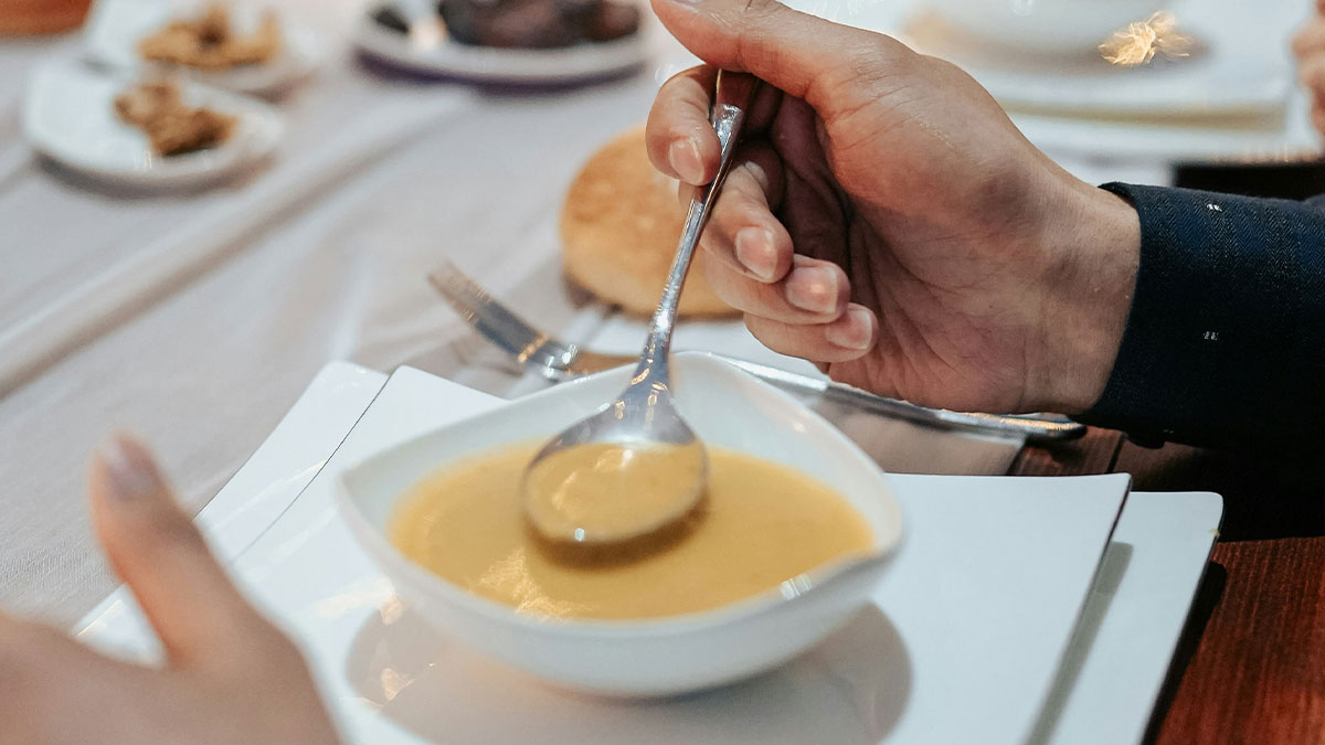 Person holding spoon over a bowl of soup at a chain restaurant, highlighting things employees warn not to order.