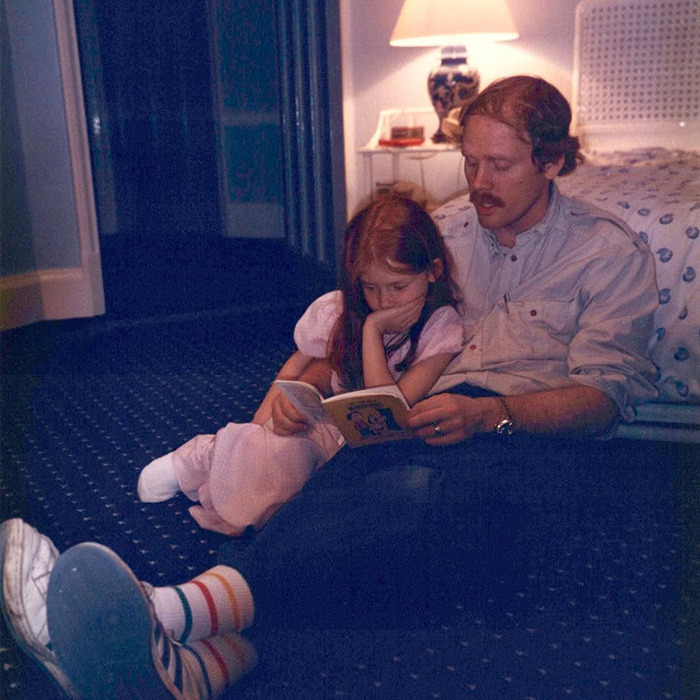 Ron Howard’s nepo baby Bryce Dallas Howard as a child reading a book with a man in a cozy dimly lit room. Ron Howard’s nepo baby Bryce Dallas Howard as a child reading a book with a man in a cozy dimly lit room.
