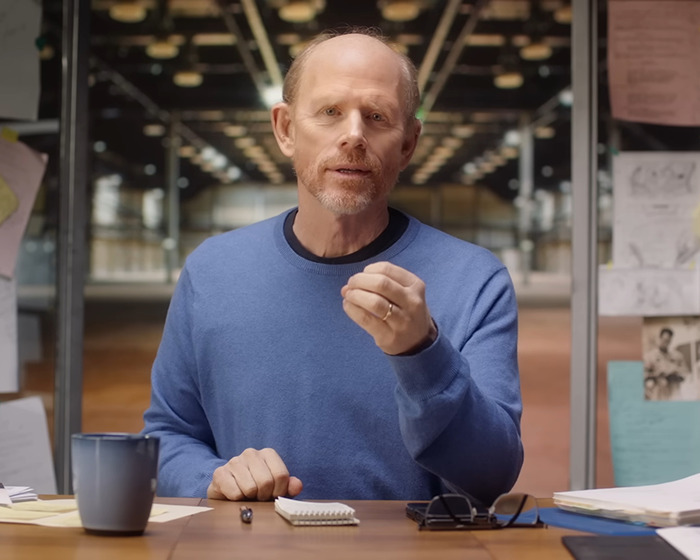 A man in a blue sweater seated at a desk with notes and a mug, discussing Ron Howard’s Nepo Baby Bryce Dallas Howard. A man in a blue sweater seated at a desk with notes and a mug, discussing Ron Howard’s Nepo Baby Bryce Dallas Howard.