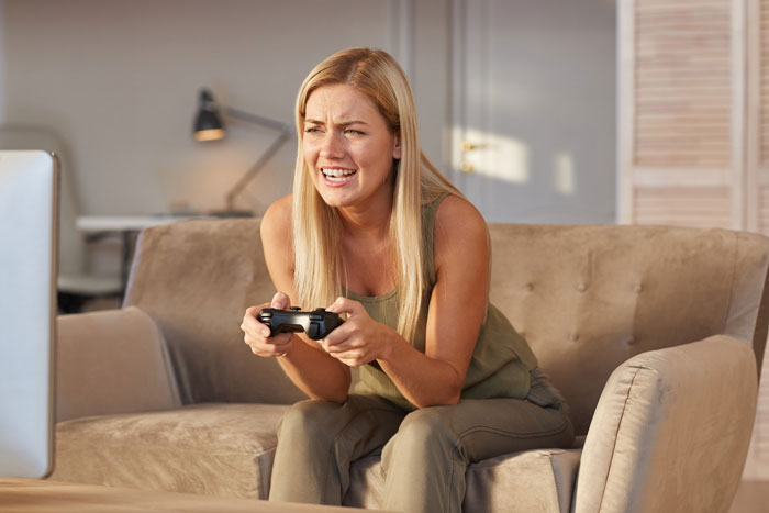 Young woman intensely gaming on a console during a late-night gaming marathon in a cozy living room. Young woman intensely gaming on a console during a late-night gaming marathon in a cozy living room.