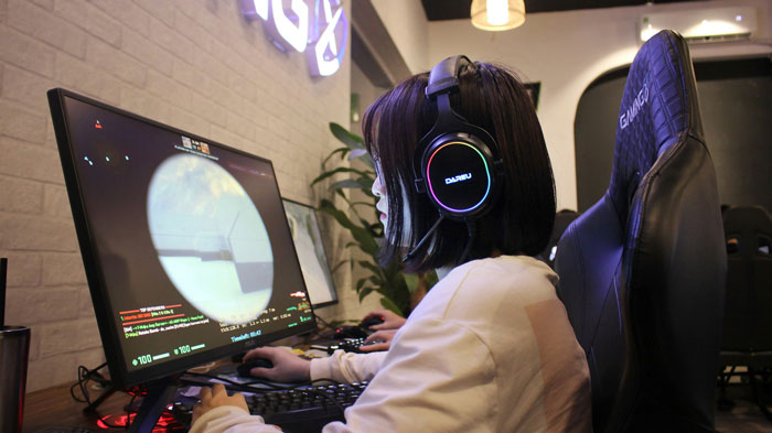 Woman wearing headphones gaming intensely on a desktop during a late-night gaming marathon at home. Woman wearing headphones gaming intensely on a desktop during a late-night gaming marathon at home.