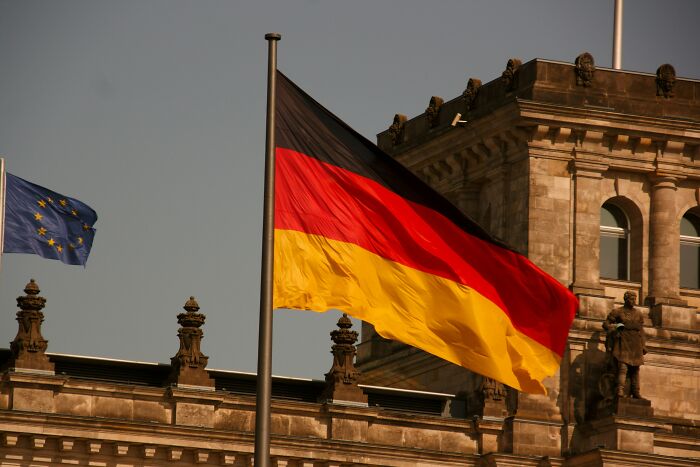 German flag waving in front of historic building with European Union flag, illustrating European netizens correcting country facts.