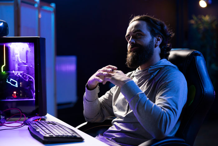Man with beard in a hoodie sitting at a computer, symbolizing lead restricting exploratory testing in game development.