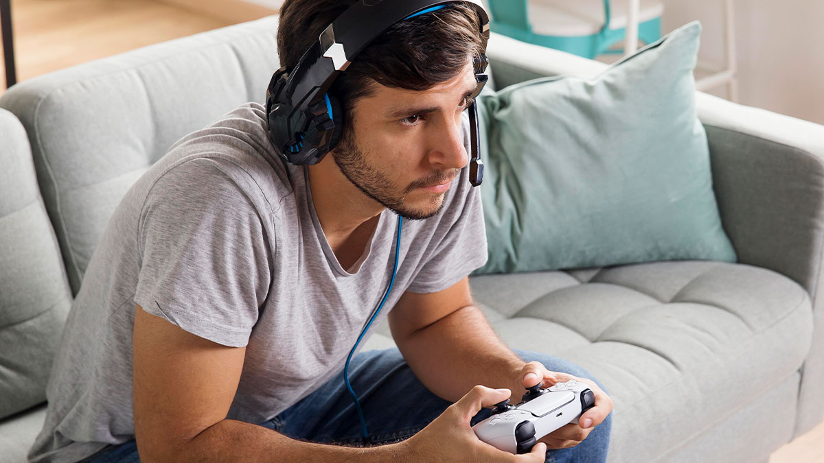 Man wearing headset focused on game controller, representing exploratory testing and developer reporting bugs in game.