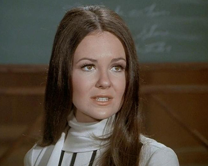 Young woman with long brown hair and a white turtleneck top in a classic sitcom scene indoors Young woman with long brown hair and a white turtleneck top in a classic sitcom scene indoors