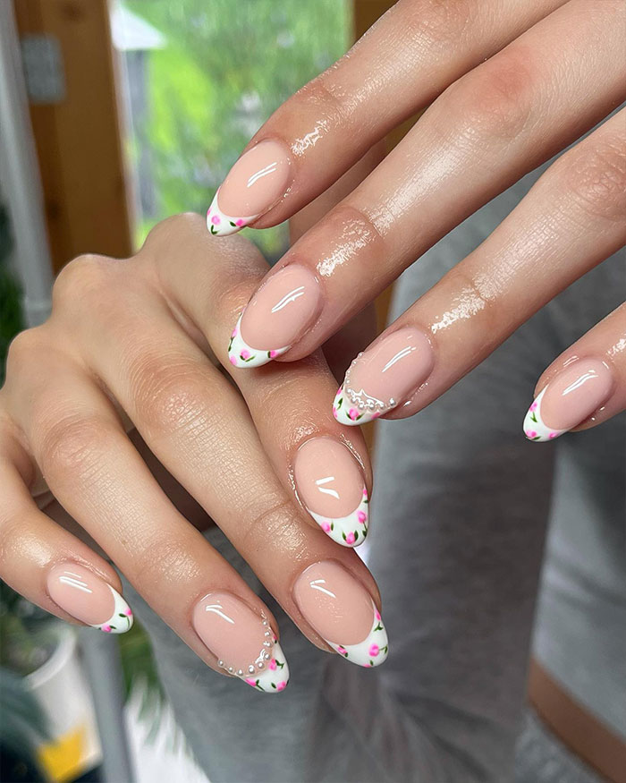 Short French tip nails with delicate floral design and rhinestones on natural nails, showcasing stylish nail art in 2025. Short French tip nails with delicate floral design and rhinestones on natural nails, showcasing stylish nail art in 2025.