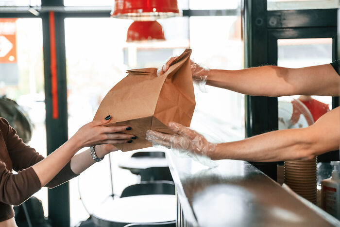 Person receiving a takeout order at a counter, illustrating moments when being shy made social interactions harder.