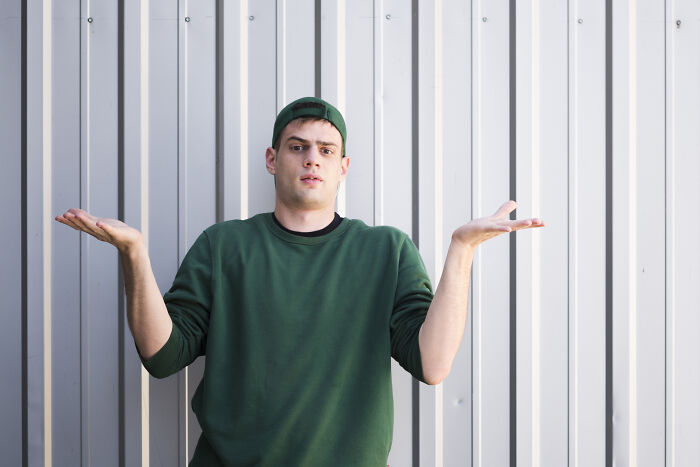 Young man shrugging with confused expression, illustrating being shy and how it made social situations worse.