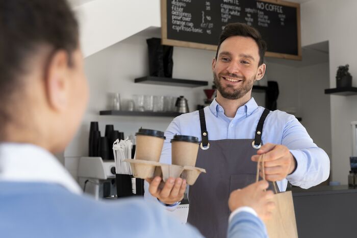 Barista handing coffee to customer in café, illustrating moments when being shy made interactions difficult.