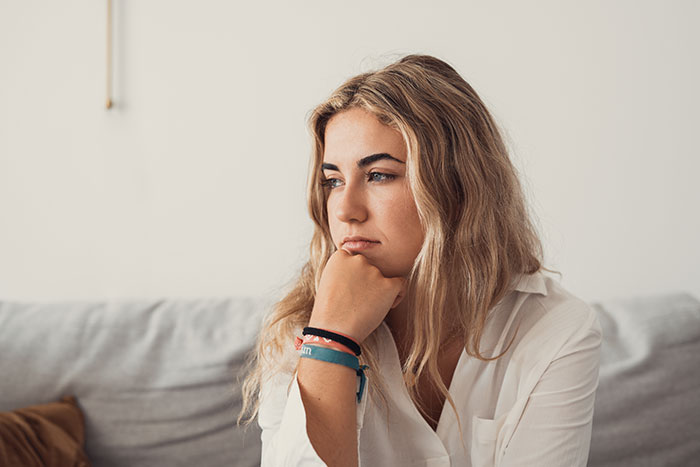 Young woman looking thoughtful and upset, reflecting on mom expecting endless babysitting from sis and shaming her trip choice Young woman looking thoughtful and upset, reflecting on mom expecting endless babysitting from sis and shaming her trip choice