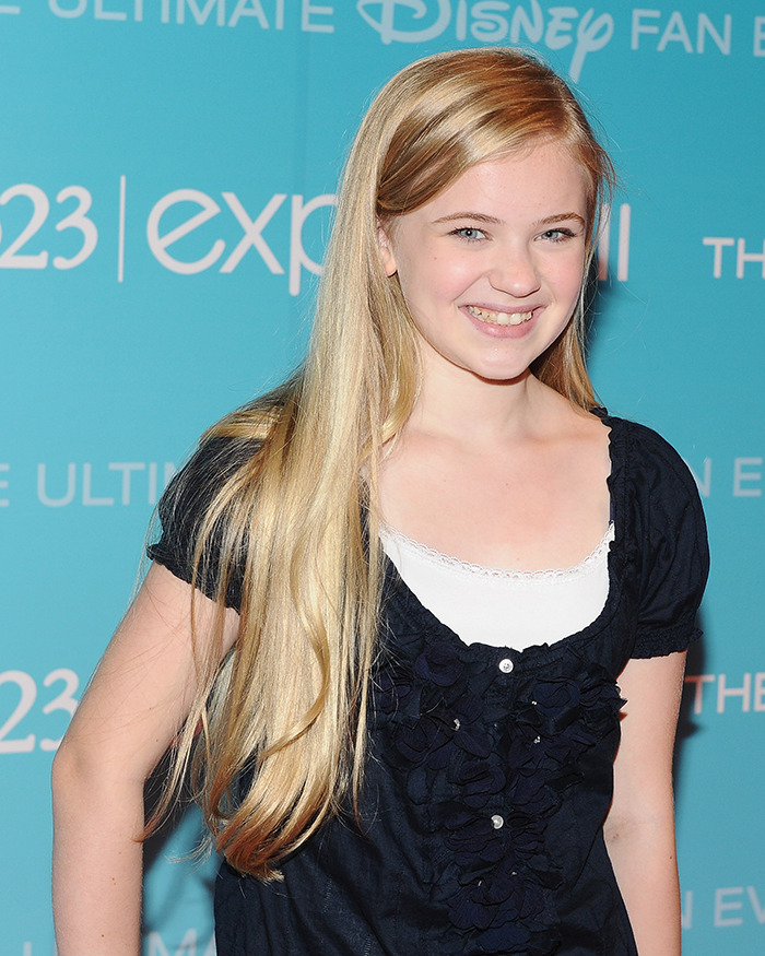 Young female child star with long blonde hair smiling at a Disney fan event, showcasing an unrecognizable transformation. Young female child star with long blonde hair smiling at a Disney fan event, showcasing an unrecognizable transformation.