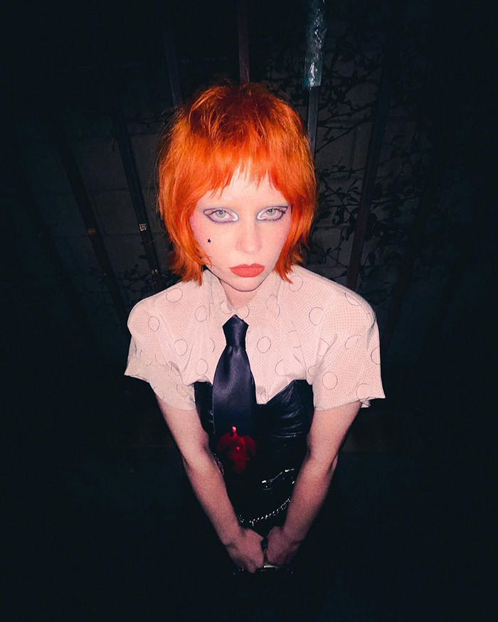Person with bright orange hair and bold makeup showing unrecognizable transformation, evoking a sinister Disney pattern vibe. Person with bright orange hair and bold makeup showing unrecognizable transformation, evoking a sinister Disney pattern vibe.