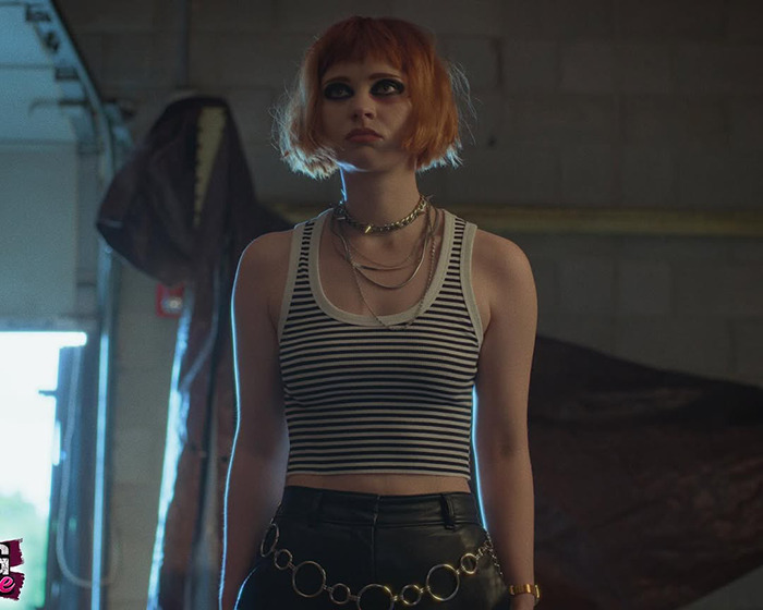 Young woman with orange hair and dark eye makeup wears striped tank top and leather pants, highlighting child star transformation. Young woman with orange hair and dark eye makeup wears striped tank top and leather pants, highlighting child star transformation.