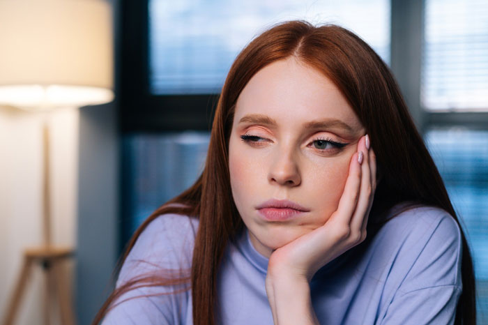 Young woman looking tired and frustrated as her sister expects her to babysit three days a week during family visit. Young woman looking tired and frustrated as her sister expects her to babysit three days a week during family visit.