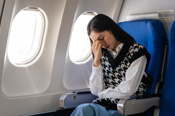 Young woman on airplane, looking stressed and tired while flying out to babysit nephew for a week. Young woman on airplane, looking stressed and tired while flying out to babysit nephew for a week.