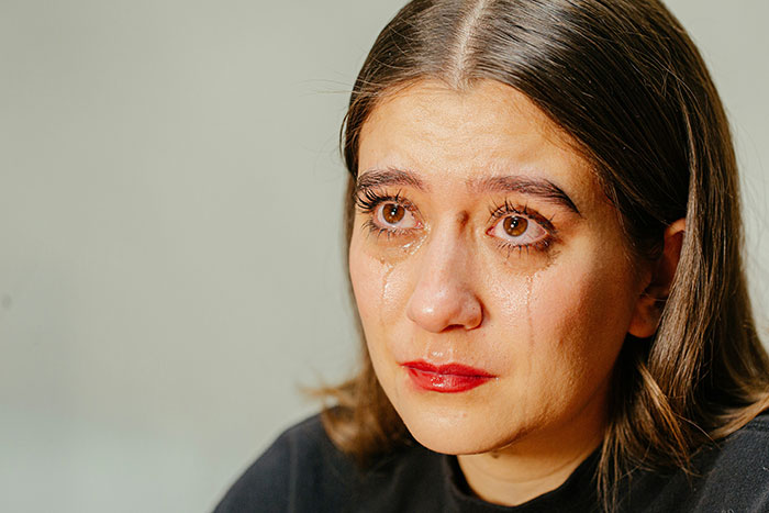 Woman with tears streaming down her face, showing sadness on graduation day after seat given away without word. Woman with tears streaming down her face, showing sadness on graduation day after seat given away without word.