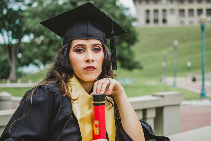 Woman in graduation gown holding diploma outdoors, looking serious on her graduation day after seat mix-up incident. Woman in graduation gown holding diploma outdoors, looking serious on her graduation day after seat mix-up incident.