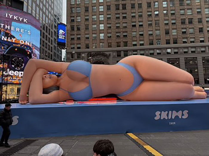Giant billboard of Bianca Censori in a daring bodysuit with hair extensions, prompting Kim K clone comments in a city square. Giant billboard of Bianca Censori in a daring bodysuit with hair extensions, prompting Kim K clone comments in a city square.