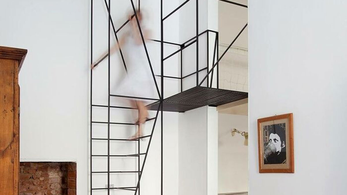 Person in a white dress descending death stairs with minimal black metal railing inside a modern white interior.