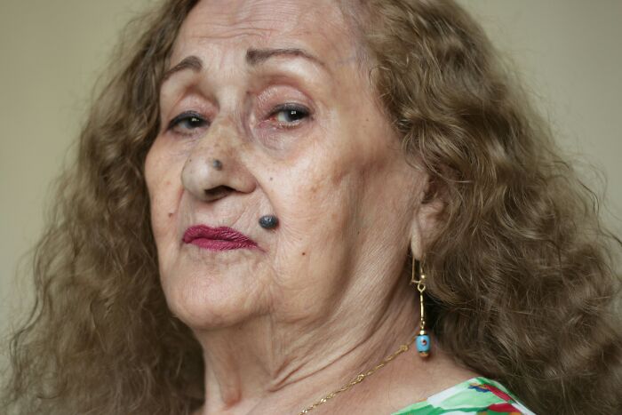 Elderly woman with curly hair and colorful earrings, reflecting on stepdaughter and ex-wife family conflict issues. Elderly woman with curly hair and colorful earrings, reflecting on stepdaughter and ex-wife family conflict issues.