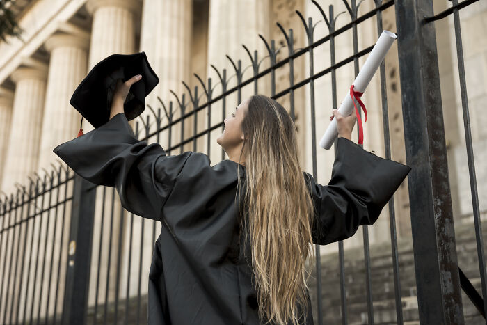 Woman in graduation gown holding diploma and cap, symbolizing wife who raised stepdaughters amid family conflict. Woman in graduation gown holding diploma and cap, symbolizing wife who raised stepdaughters amid family conflict.