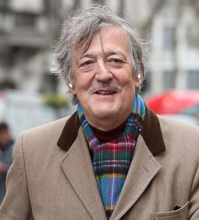 Stephen Fry outdoors wearing a beige coat and colorful scarf, associated with Stephen Fry gives brutal takedown of J.K. Rowling. Stephen Fry outdoors wearing a beige coat and colorful scarf, associated with Stephen Fry gives brutal takedown of J.K. Rowling.