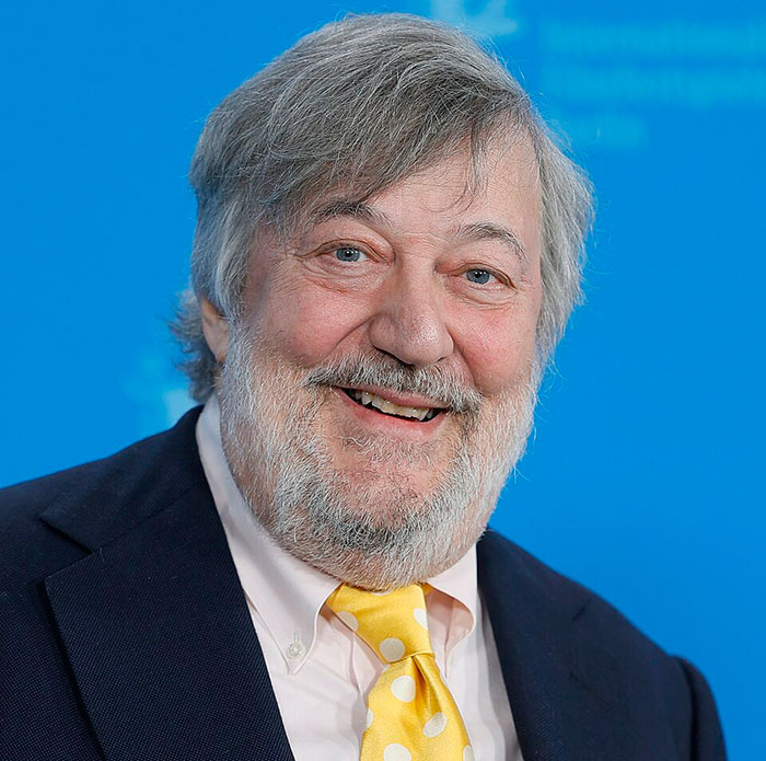Stephen Fry smiling in a suit and yellow tie, known for giving a brutal takedown of J.K. Rowling. Stephen Fry smiling in a suit and yellow tie, known for giving a brutal takedown of J.K. Rowling.