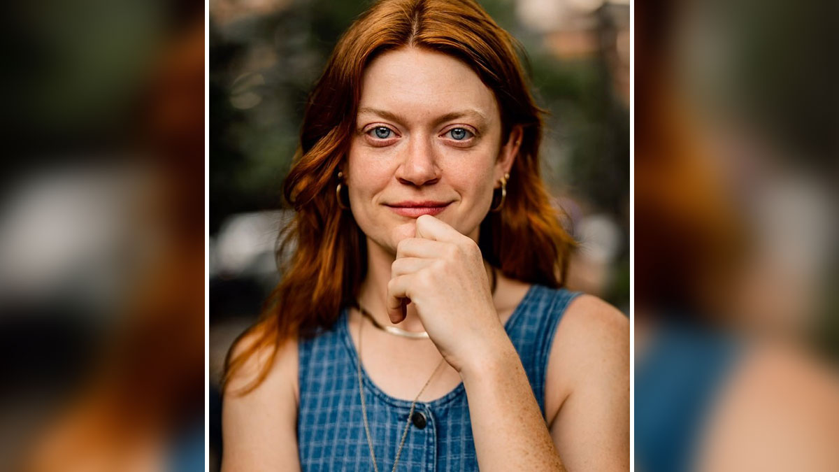 Young woman with red hair posing candidly, captured by photographer moments before stunning portrait photo session.