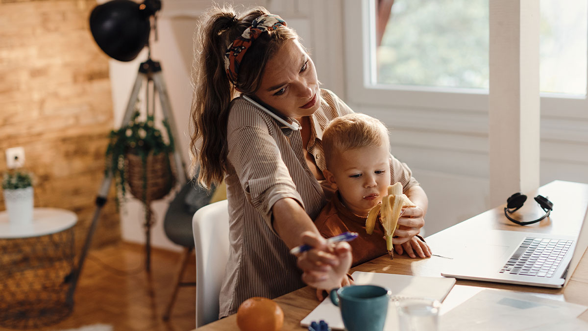 Woman multitasking babysitting toddler while working from home, illustrating child-free lady and babysitting concerns.
