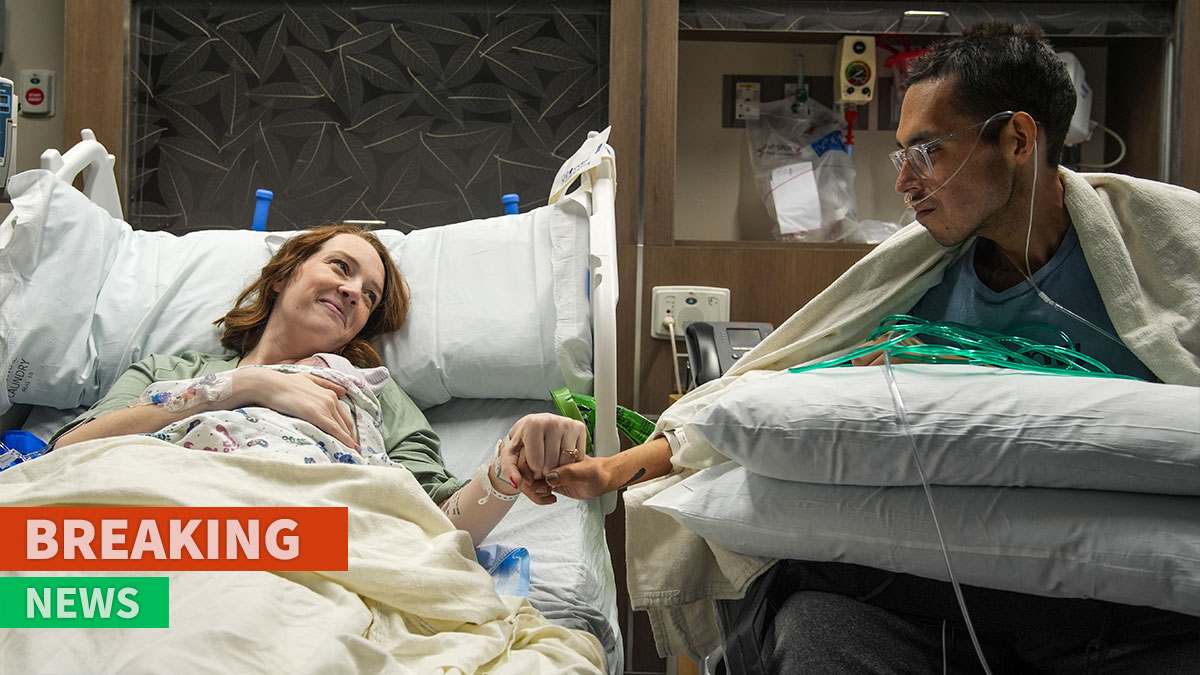 Tanner Martin holding hands with his partner in hospital beds, oxygen tubes visible during a serious moment