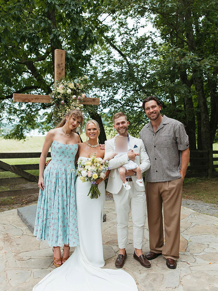 Taylor Swift and Travis Kelce at a wedding celebration, standing outdoors near a wooden cross decorated with flowers. Taylor Swift and Travis Kelce at a wedding celebration, standing outdoors near a wooden cross decorated with flowers.
