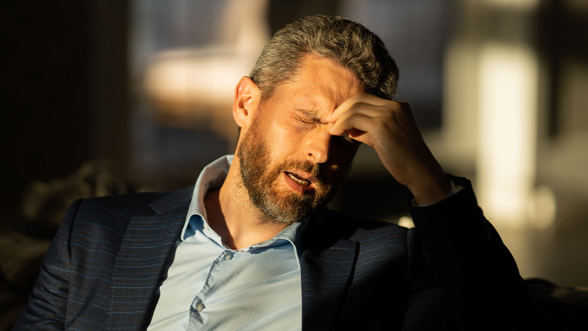 Man in a suit with eyes closed, pinching his nose in frustration, illustrating things learned embarrassingly late stories.