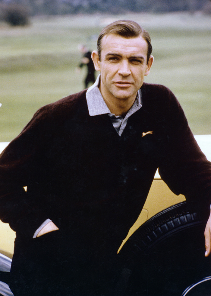 Sean Connery in a dark sweater leaning on a tire outdoors, highlighting James Bond actor viral photos debate. Sean Connery in a dark sweater leaning on a tire outdoors, highlighting James Bond actor viral photos debate.