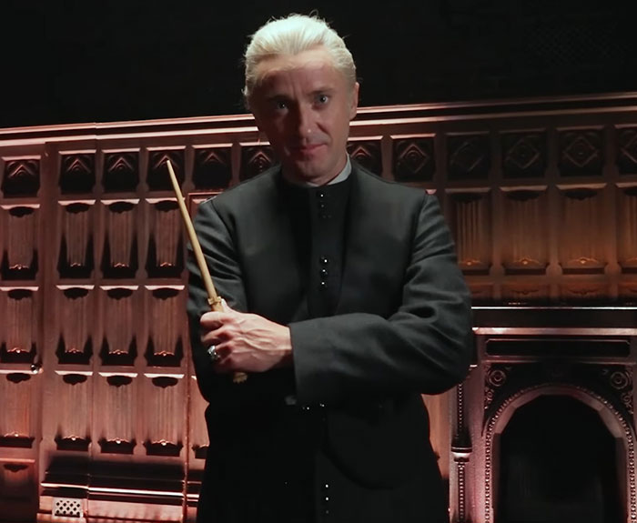 Tom Felton dressed as Draco Malfoy holding a wand on a Harry Potter set with an intense expression. Tom Felton dressed as Draco Malfoy holding a wand on a Harry Potter set with an intense expression.
