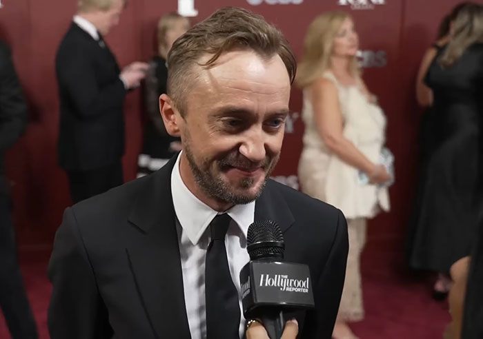 Tom Felton wearing a black suit speaking to Hollywood Reporter at a red carpet event, sparking Harry Potter fan reactions. Tom Felton wearing a black suit speaking to Hollywood Reporter at a red carpet event, sparking Harry Potter fan reactions.