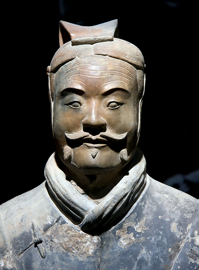Close-up of a 2000-year-old statue with a mustache, representing ancient historical art damaged by a tourist incident.