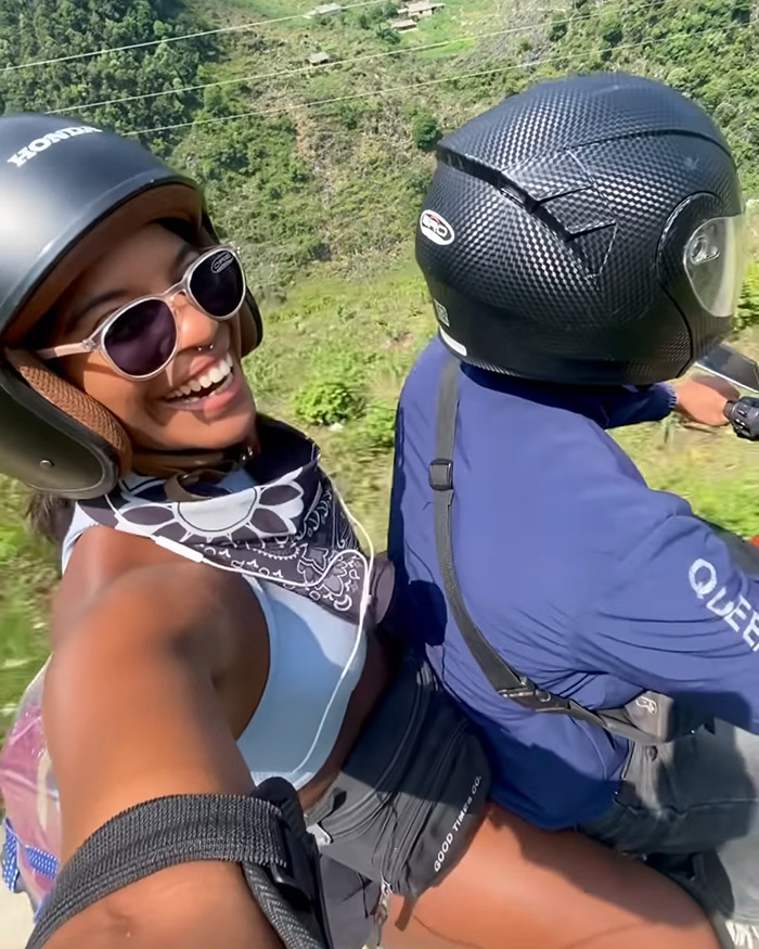 Smiling tourist wearing helmet and sunglasses on a motorbike ride near an active volcano during adventurous travel. Smiling tourist wearing helmet and sunglasses on a motorbike ride near an active volcano during adventurous travel.