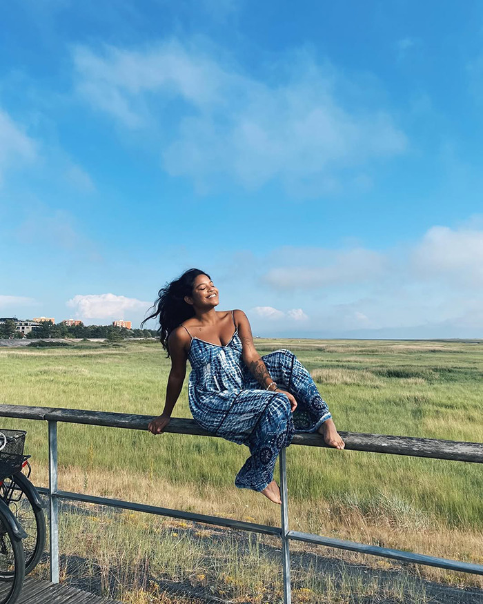 Young tourist sitting on railing outdoors, smiling under blue sky, capturing moment before abandoned near active volcano incident. Young tourist sitting on railing outdoors, smiling under blue sky, capturing moment before abandoned near active volcano incident.