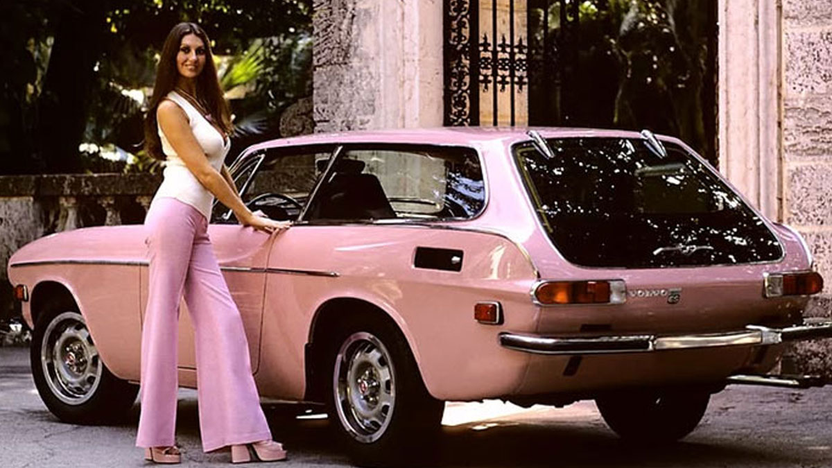 Woman in pink pants posing next to a vintage pink car in a rare historical photo from past decades.