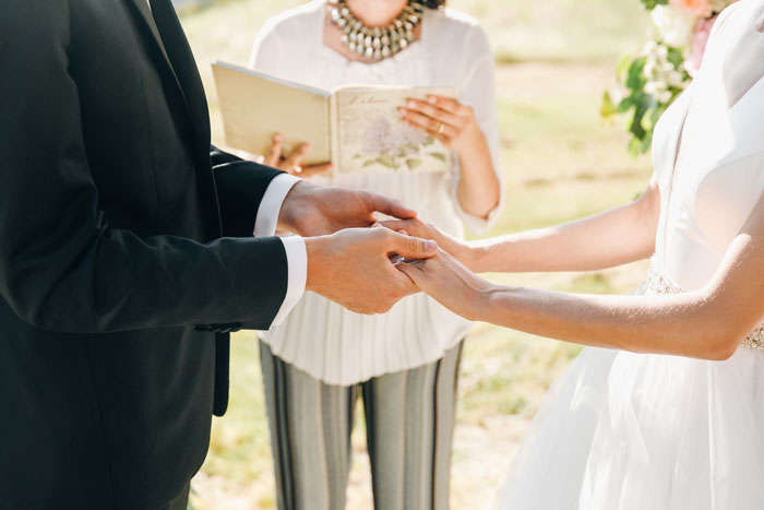 Couple holding hands during wedding ceremony with guests shocked and confused after eloping three years earlier.